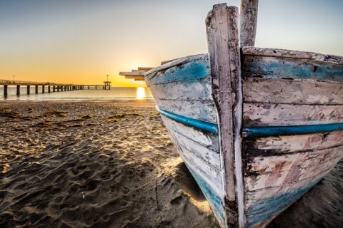 Photo of seafront with old boat and walking bridge